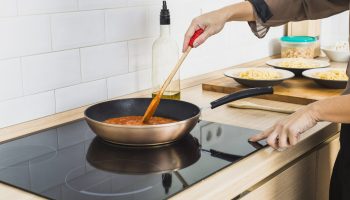 person-mixing-sauce-pan-stove